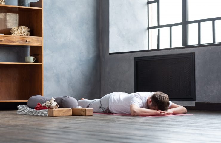 Man resting after yoga practice on floor in makarasana.