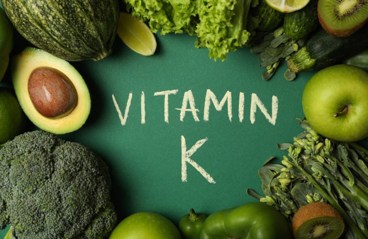 Vegetables, fruits and text Vitamin K on green background
