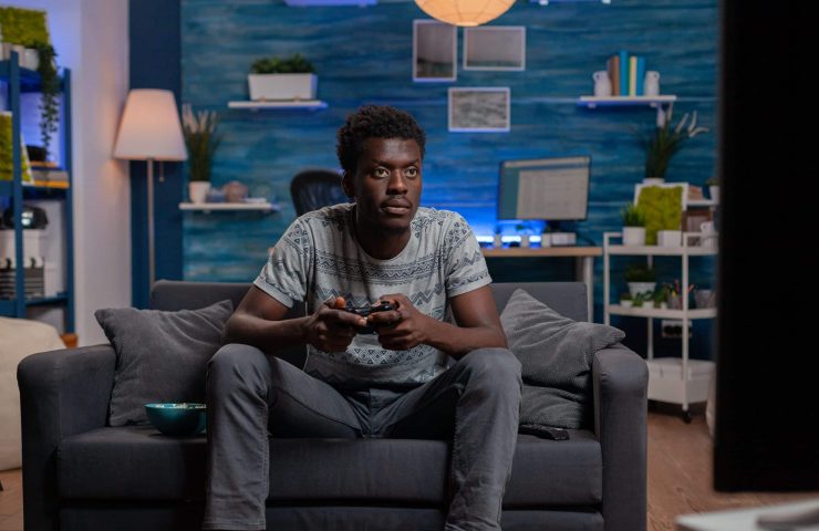 African american player young man holding gaming joystick playing online videogames