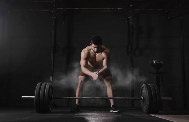 Crossfit athlete clapping hands and preparing for weight lifting at the gym