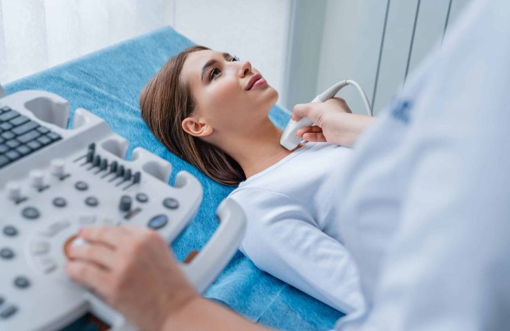 Woman getting her neck examined by female doctor using ultrasound scanner at modern clinic