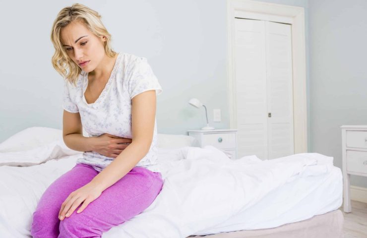 Young woman having stomach pain in bed at bedroom