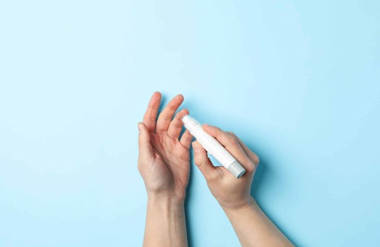 Female checking blood sugar level on blue background