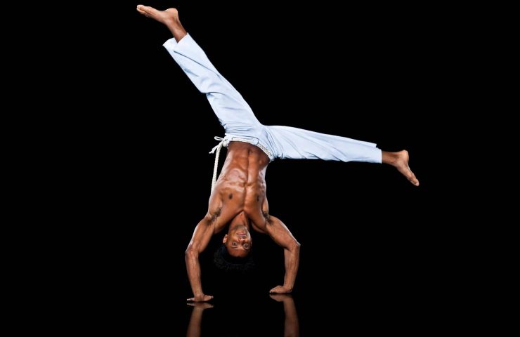 Man practising capoeira, in handstand position