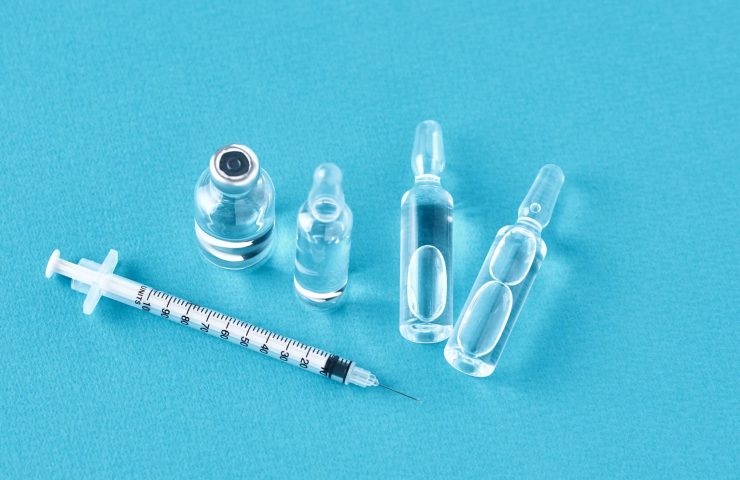 Syringes and medicine bottles with medication on a blue background
