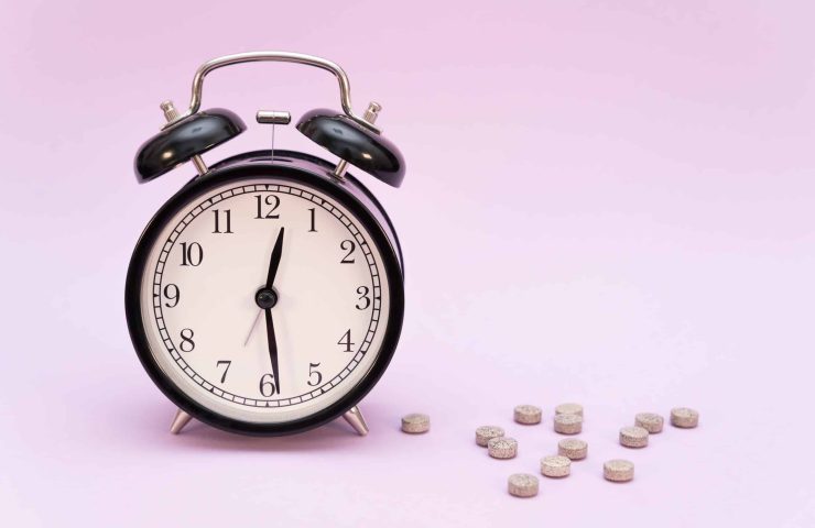 alarm-clock-and-melatonin-pills-on-colored-backgro-2022-11-15-02-33-09-utc